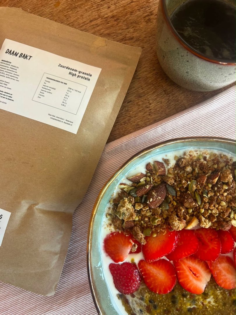 Daan Bakt High Protein zuurdesemgranola naast een yoghurtbowl met passievrucht-mango jelly en koffie