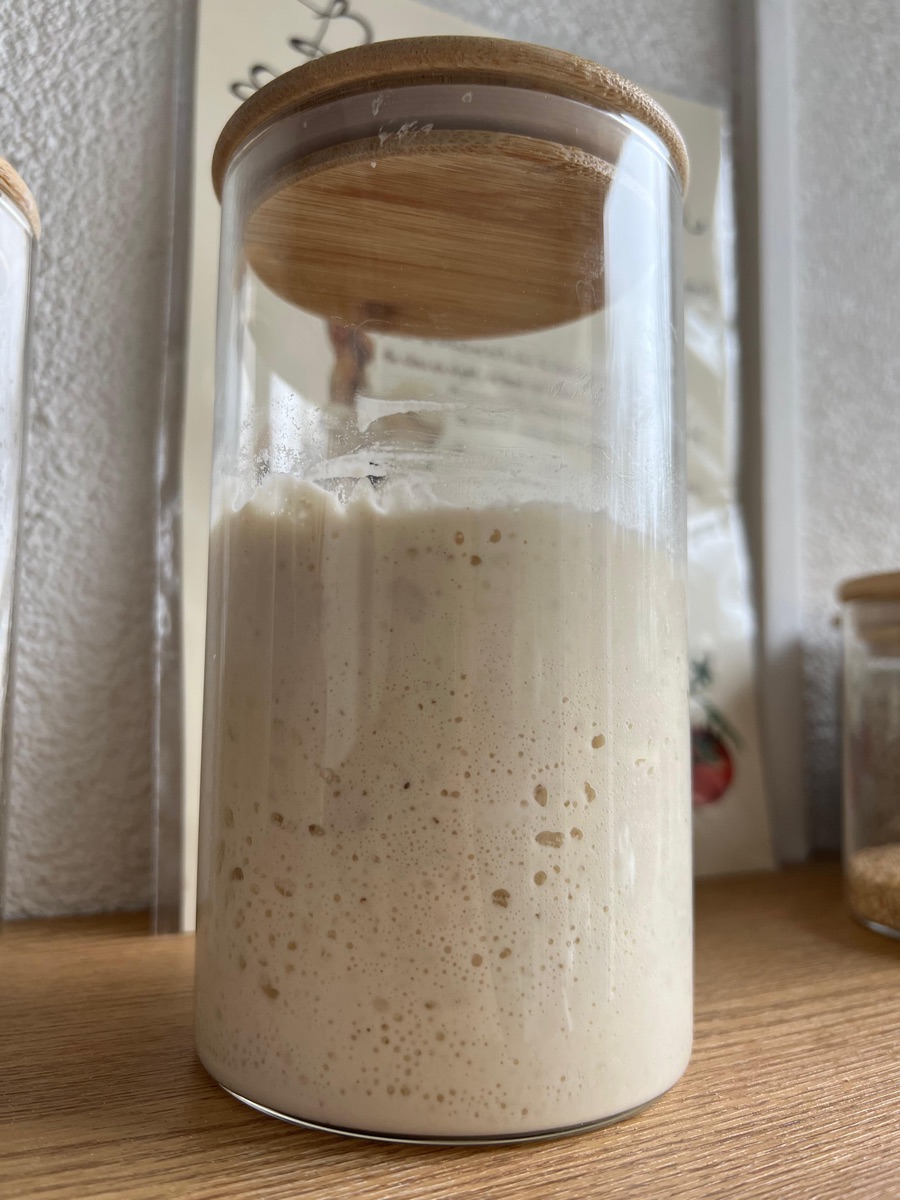 Zuurdesemstarter in een glazen pot, bubbelend na het voeren
